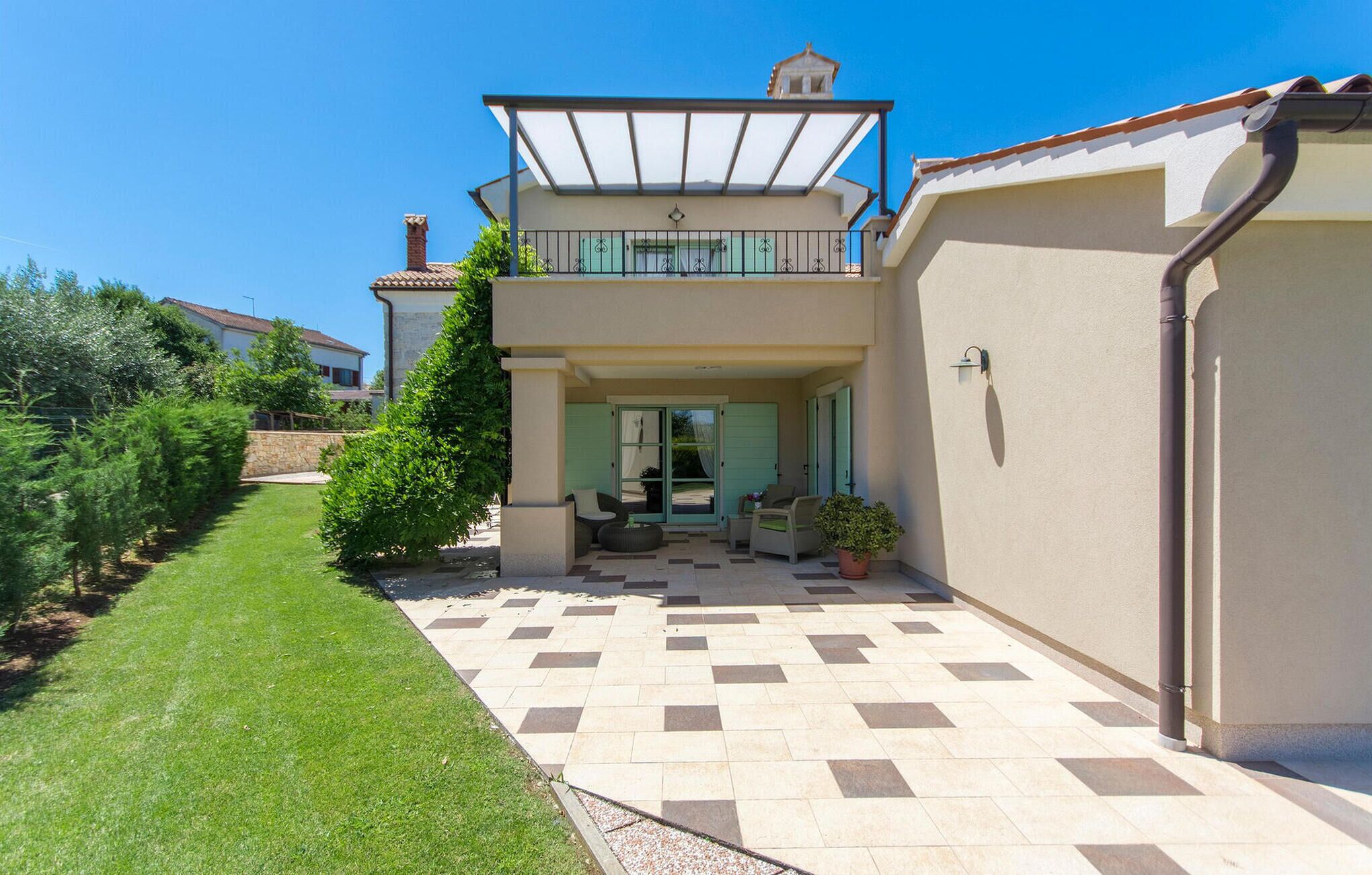 Een tweelaags huis met een patio, een balkon en een tuin.