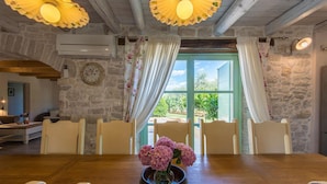 A dining area with a wooden table, chairs, and a vase of flowers. There is a clock on the wall and a window with curtains. - Beautiful home in Tar (Tar)