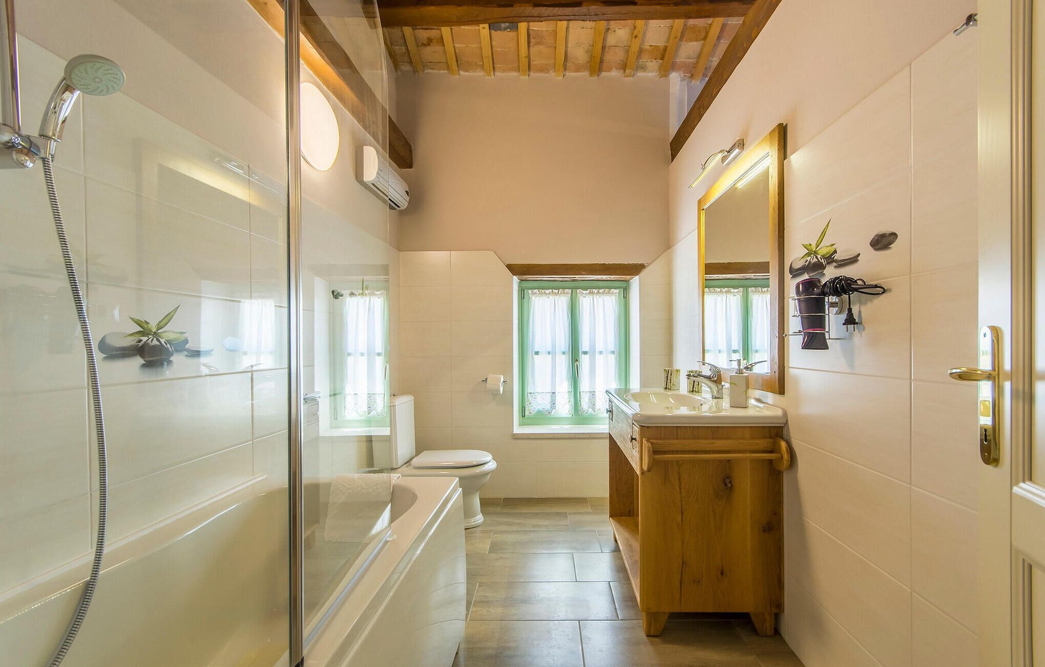 Ein Badezimmer mit Duschkabine, Toilette, Waschbecken und Fenster.