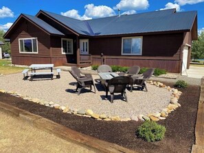Situated on a well-maintained lawn, this cabin features a cozy front porch with a bench and table, surrounded by six chairs.
