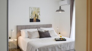 A modern bedroom with a large bed, a bedside table with a lamp, a small potted plant, and a tray with a glass of wine. - 3 bedroom lovely home in Nin (Nin)
