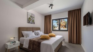 A modern bedroom with a bed, a bedside table, a lamp, a window with curtains, and a painting on the wall. - 4 bedroom awesome home in Sukosan (Sukosan)