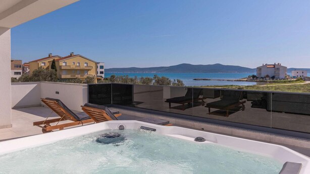 A rooftop terrace with a hot tub, lounge chairs, and a view of the sea and buildings. - 4 bedroom awesome home in Sukosan (Sukosan)