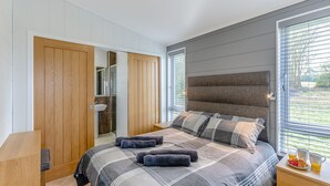 A bedroom with a large bed, a wooden wardrobe, a bedside table with a lamp, and a window with blinds. - 2 bedroom accommodation in Chadwick, near Worcester (Chadwick, near Worcester)