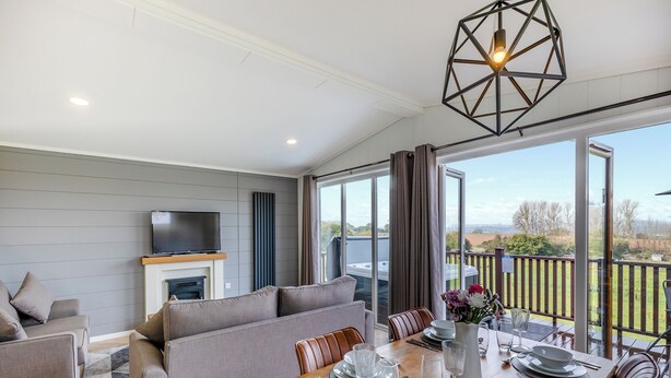 A modern living room with a sofa, a dining table set for four, and a fireplace. - 2 bedroom accommodation in Chadwick, near Worcester (Chadwick, near Worcester)