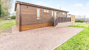 A single-story wooden building with a gravel driveway and a wooden deck. - 2 bedroom accommodation in Chadwick, near Worcester (Chadwick, near Worcester)