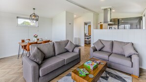 A modern living room with two grey sofas, a wooden coffee table, and a dining area with a wooden table and chairs. - 2 bedroom accommodation in Chadwick, near Worcester (Chadwick, near Worcester)