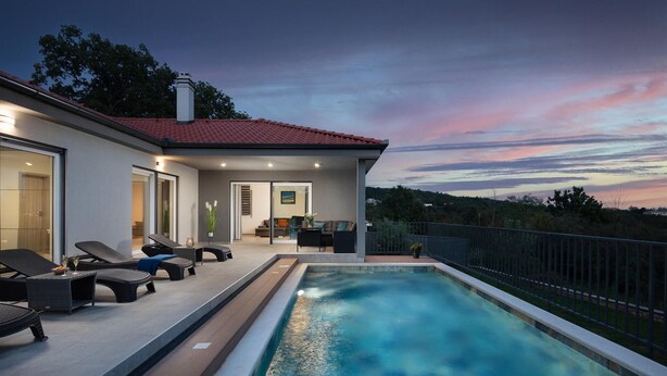 Ein modernes Haus mit Schwimmbad, Sitzgelegenheit im Freien und Blick auf die Landschaft.