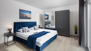 Ein modernes Schlafzimmer mit einem großen Bett, einem Nachttisch, einem Spiegel und Blick auf einen Steg.