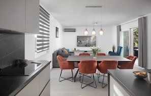 A modern kitchen with a dining area, featuring a marble countertop, a large dining table with six chairs, and pendant lighting. - Luxurious home in Labin (Labin)