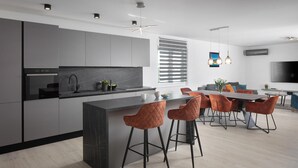 Eine moderne Küche mit einer zentralen Kochinsel, Barhocker und einem Essbereich mit Tisch und Stühlen.