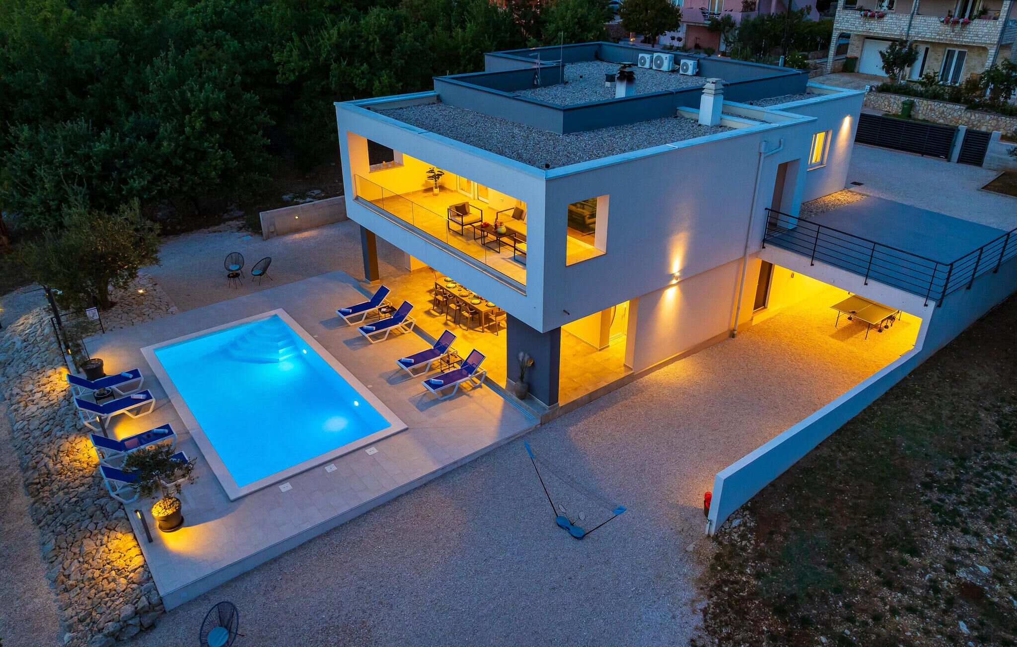 A modern two-story house with a rooftop terrace, a swimming pool, and outdoor seating.
