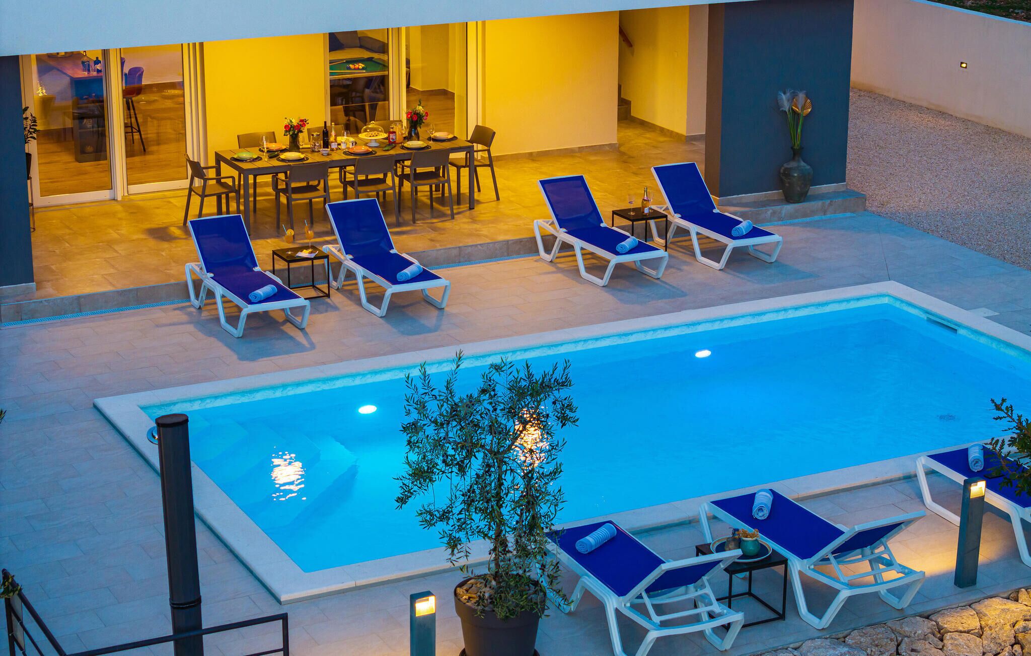 Un espace piscine avec des chaises longues et une table à manger.