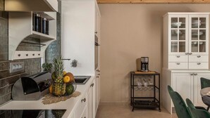 Une cuisine équipée d’une cuisinière moderne, d’une machine à café et d’un panier de fruits posé sur le comptoir.