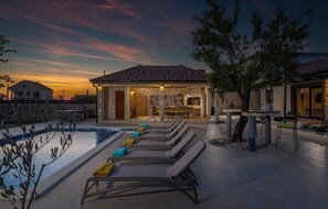 A poolside area with lounge chairs and a stone building with a tiled roof. - Amazing home in Zemunik Donji with WiFi (Zemunik Donji)