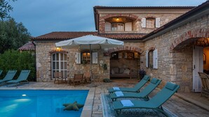 Ein Steinhaus mit Pool, Außenbereich zum Sitzen und einer überdachten Terrasse.
