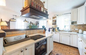 A kitchen with white cabinets, a built-in oven, a stove, and various kitchen utensils and appliances. - Beautiful home in Visnjan (Visnjan)