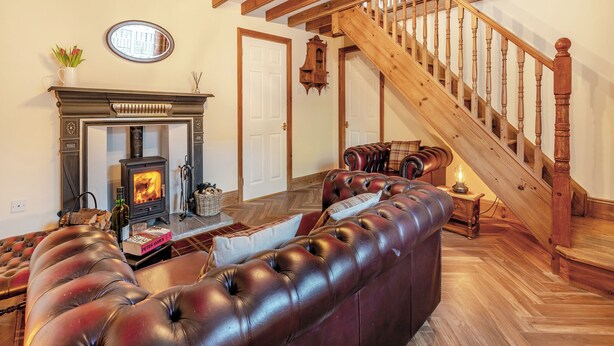A cozy living room with a fireplace, leather sofa, wooden staircase, and a chandelier. - 3 bedroom accommodation in Fir Tree, near Crook (Fir Tree, near Crook)