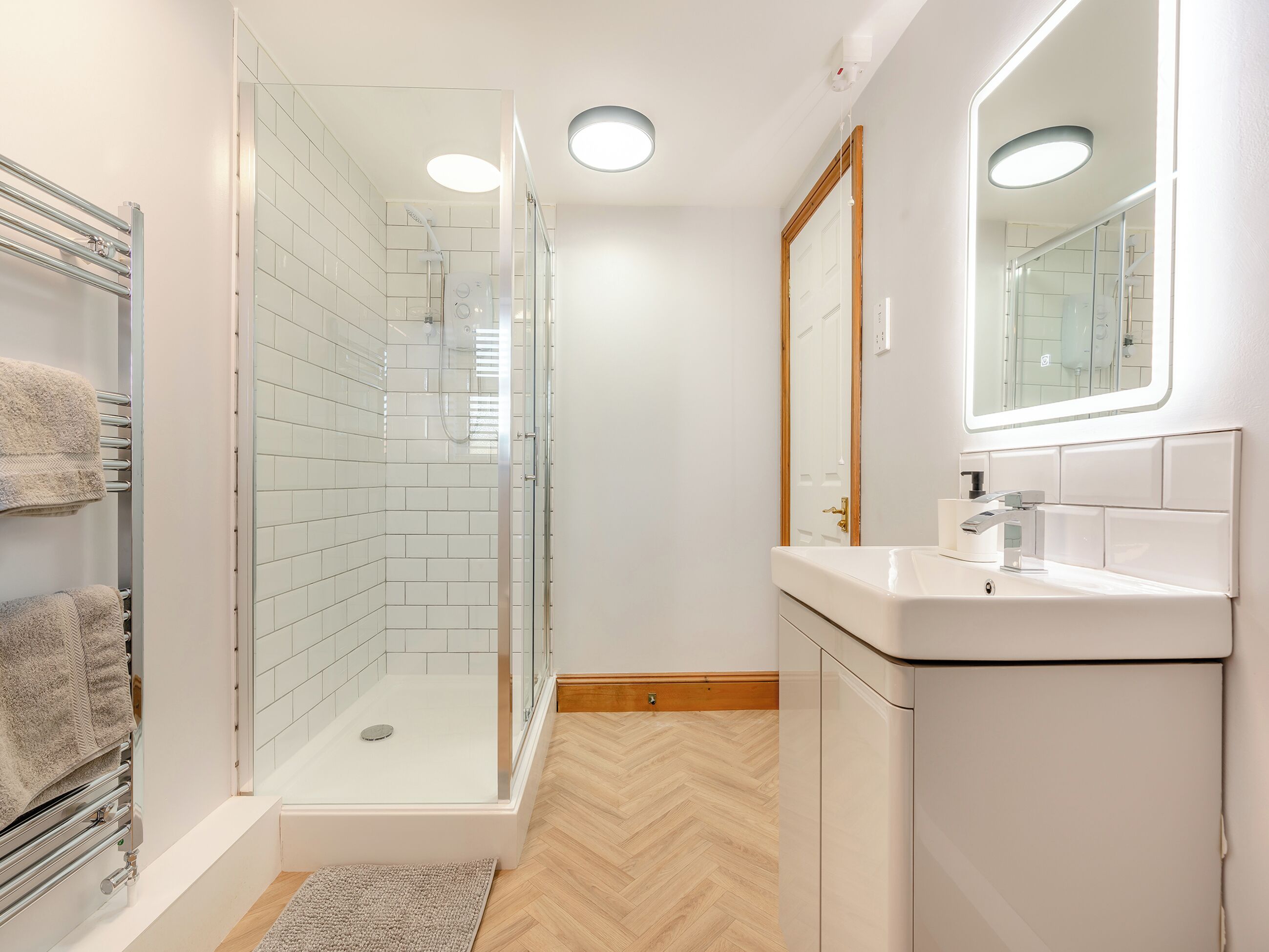 A modern bathroom with a glass-enclosed shower, a white sink, and a mirror above it.