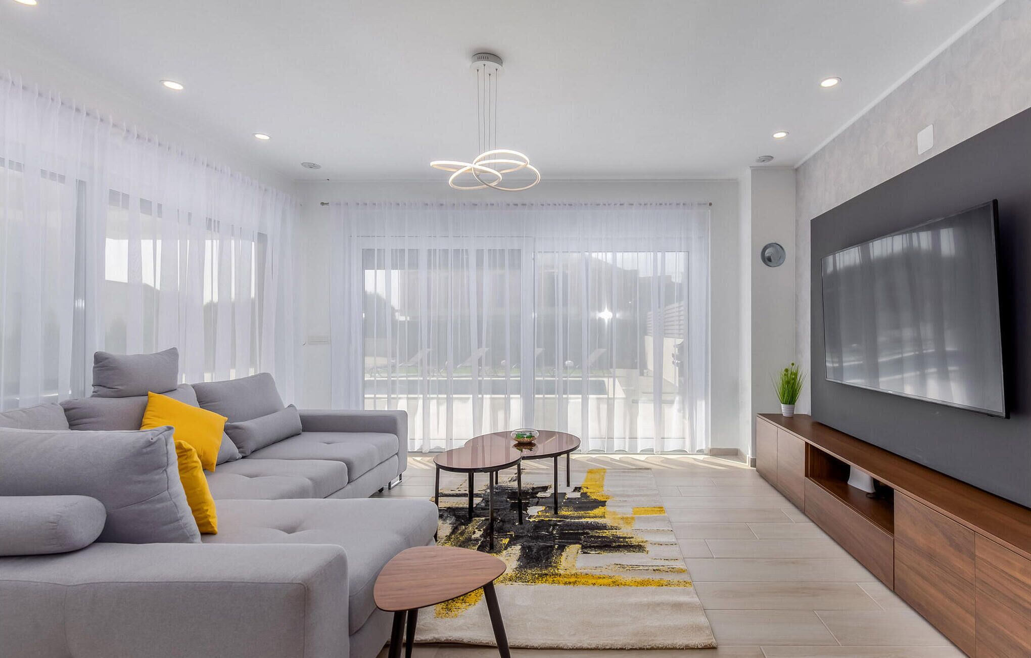 Una sala moderna con un sofá gris, una mesa de centro y un televisor montado en la pared.