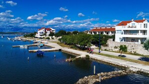 Una zona costera con un puerto deportivo, edificios blancos con tejados rojos y un cielo azul despejado.