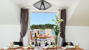 Mesa lista para una comida con vista al mar y follaje.