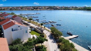 Un pueblo costero con un puerto deportivo, edificios blancos con techos rojos y un cielo azul despejado.