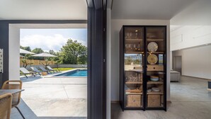 A modern living space with a pool, lounge chairs, and a glass cabinet with decorative items. - 3 bedroom awesome home in Krsan (Krsan)