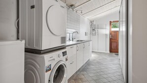 A laundry area with a Siemens washing machine, a sink, and a wooden door leading to another room.