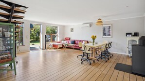 A spacious living area with a dining table, red sofa, and a fireplace.