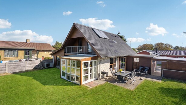 A modern house with a large glass patio, a sloped roof, and a fenced backyard.