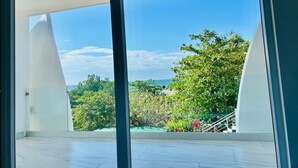 Ein modernes Interieur mit großen Fenstern, Blick auf Grünflächen und einen Pool, sowie eine Treppe zu einem Außenbereich.
