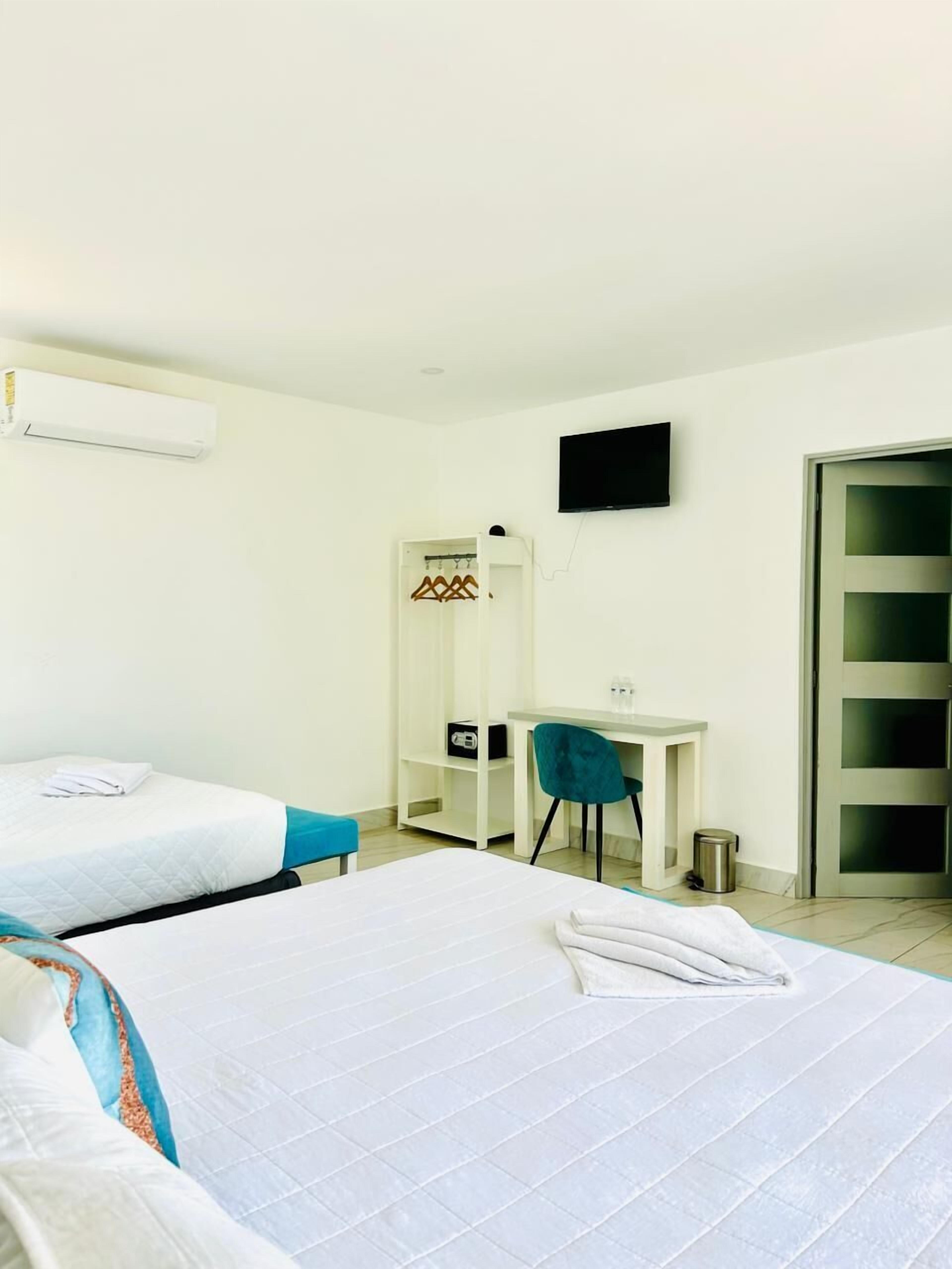 Una habitación de hotel con dos camas, un escritorio, una silla, un televisor y un armario.