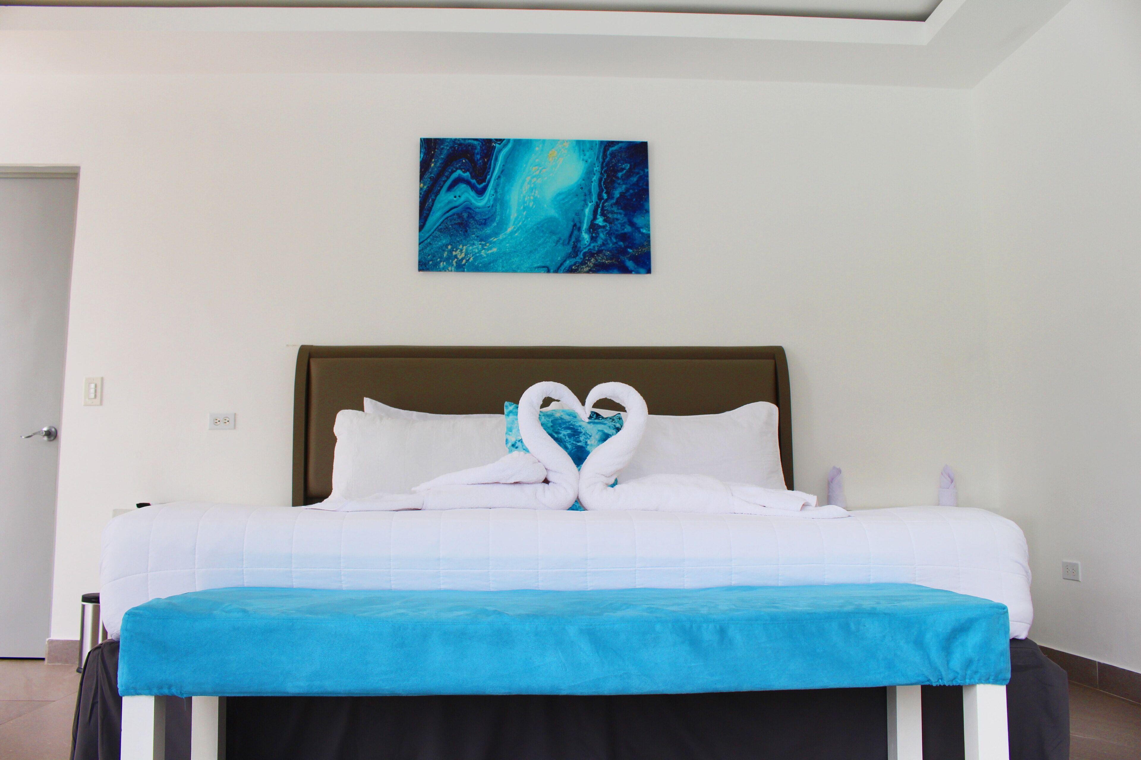 Una habitación de hotel con una cama, una colcha azul y un cuadro en la pared.