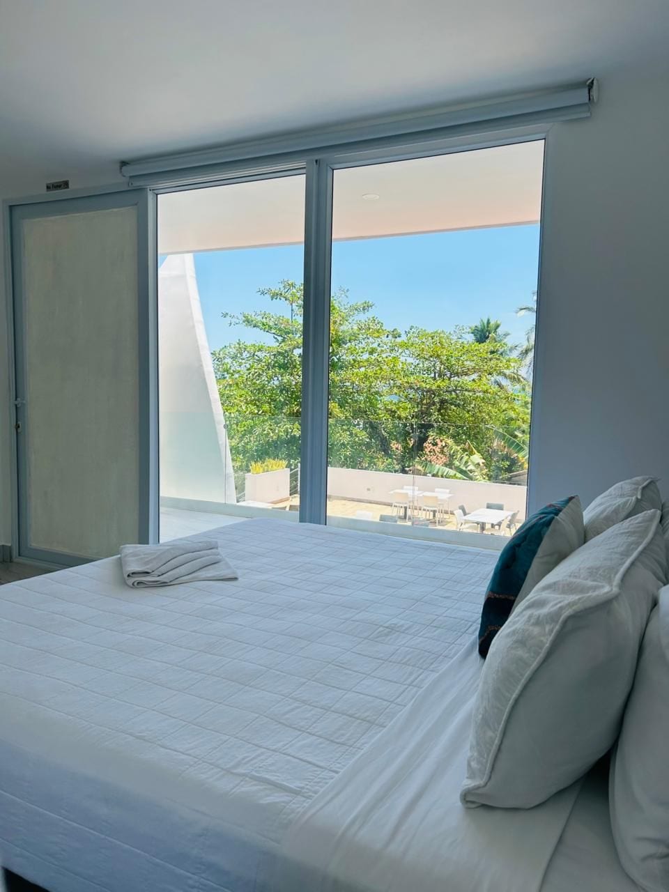 A bedroom with a large bed, a sliding door, and a view of the outdoors.