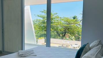 A bedroom with a large bed, a sliding door, and a view of the outdoors.