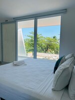 A bedroom with a large bed, a sliding door, and a view of the outdoors.