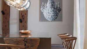 Un comedor con una mesa de madera, sillas y una lámpara moderna.