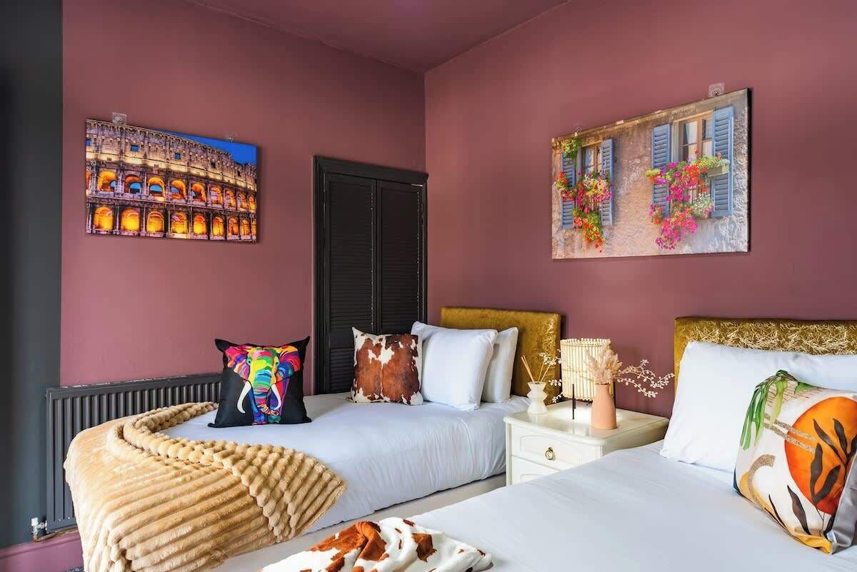 A hotel room with two beds, a large window, and artwork on the walls.