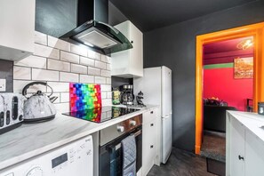 Een moderne keuken met een inbouwoven, een waterkoker en een kleurrijke achterwand.