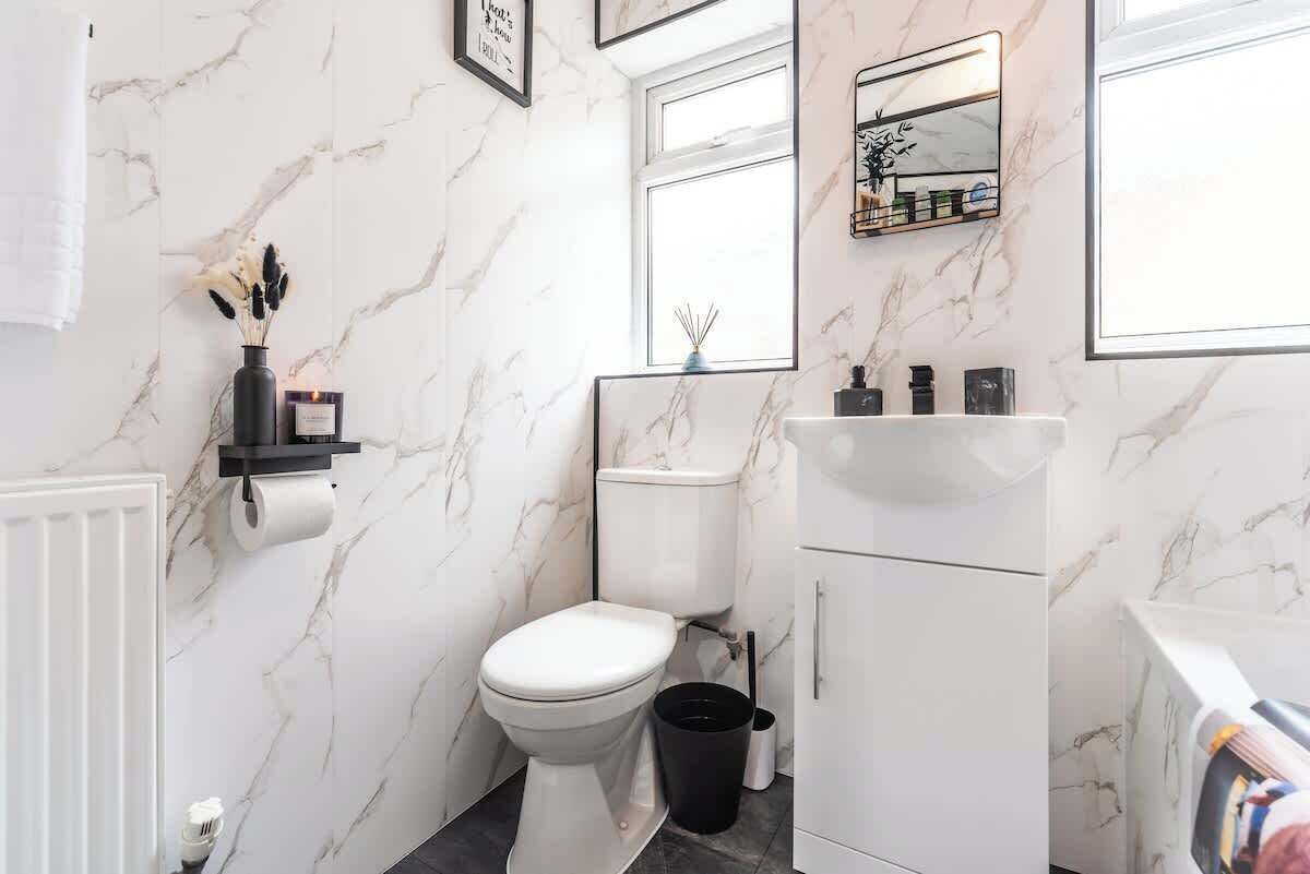 A modern bathroom with a toilet, sink, and mirror.