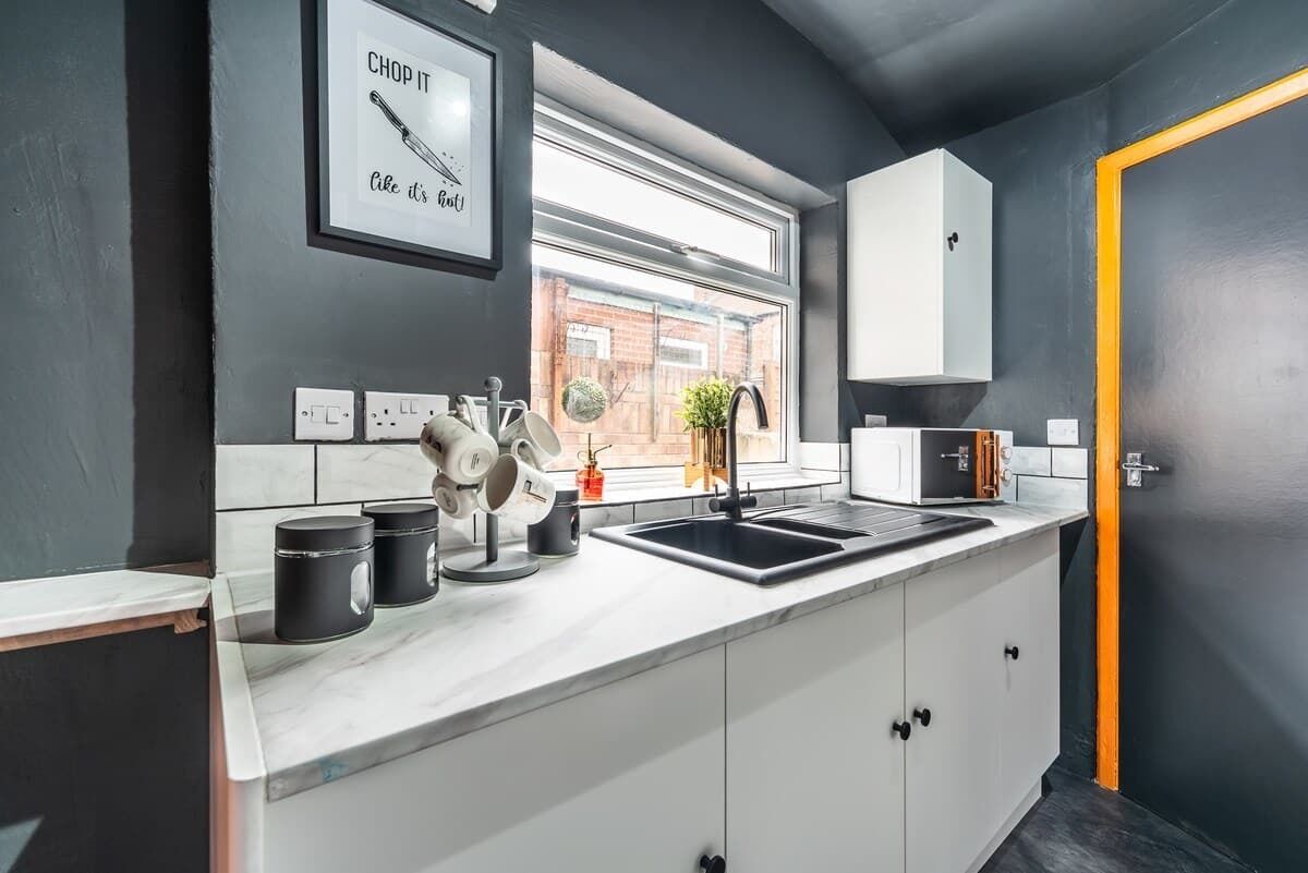 A modern kitchen with a window, white cabinets, and a black countertop.