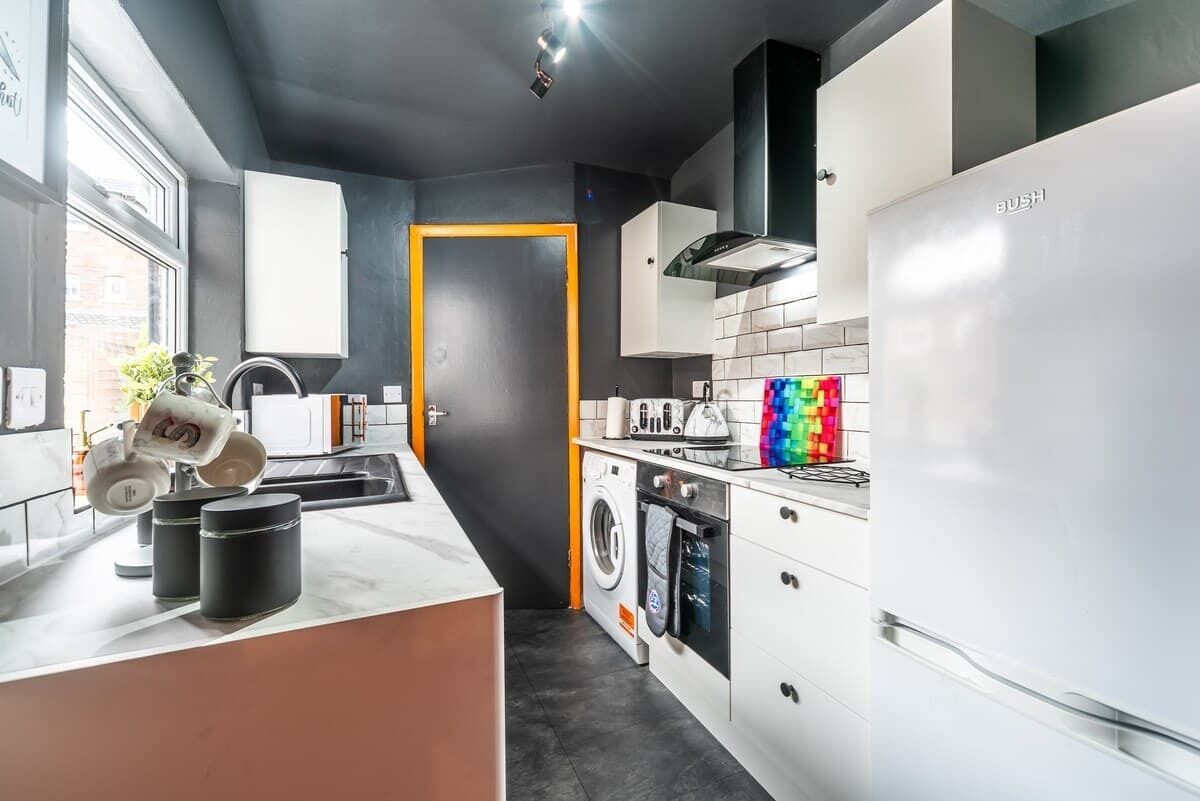 A modern kitchen with a washing machine, a refrigerator, and a microwave.