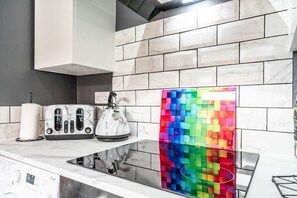 Een moderne keuken met een marmeren spatwand, een kleurrijke glazen spatwand en een ingebouwde kookplaat.