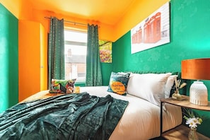 A room with a bed, a nightstand, a lamp, and a window with curtains. - Central Hull Stylish Home w/ Garden + Free Street Parking (Kingston upon Hull)