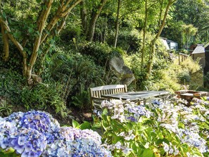Un jardin avec un banc en bois et des hortensias.
