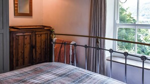 Un dormitorio con una cama, un armario de madera, un espejo, una ventana con cortinas y una lámpara roja.