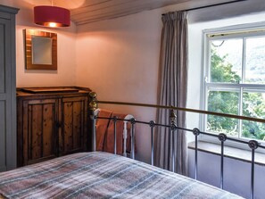 A bedroom with a bed, a wooden wardrobe, a mirror, a window with curtains, and a red lamp. - 1 bedroom accommodation in Tremadog, near Porthmadog (Tremadog, near Porthmadog)
