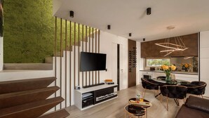 A modern living room with a staircase, a flat-screen TV, a dining area, and a kitchen. - Gorgeous home in Nin with sauna (Nin)