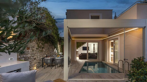 A modern outdoor pool area with a stone wall and a dining setup. - Gorgeous home in Nin with sauna (Nin)